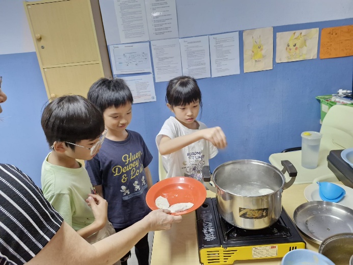 A group of children cooking in a kitchen

Description automatically generated