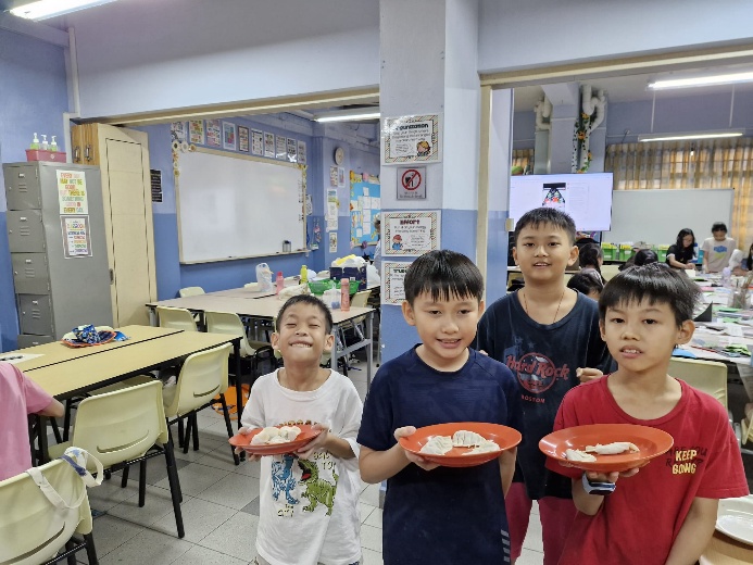 A group of children holding plates in a classroom

Description automatically generated