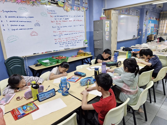 A group of children sitting at tables in a classroom

Description automatically generated