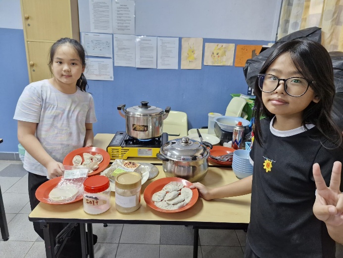 Two girls standing next to a table with food on it

Description automatically generated